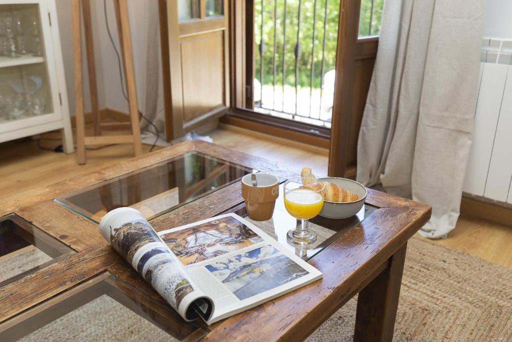 Una mesa de café con un libro y un vaso de jugo de naranja. en El Roble by BeValle, en El Pueyo de Jaca