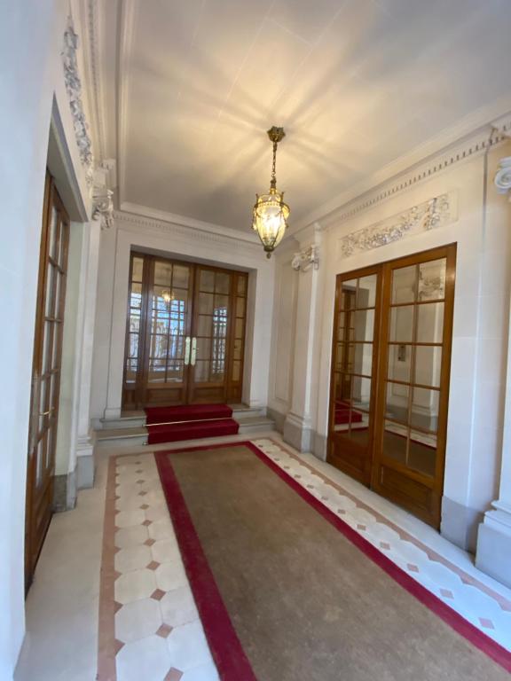 un couloir avec un lustre et un tapis rouge dans l'établissement Paris - Appartement - 16eme, à Paris