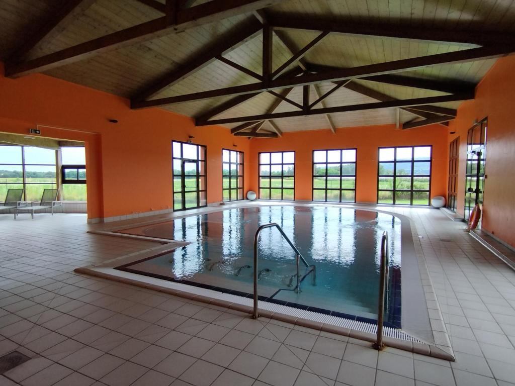 een groot zwembad in een grote ruimte met oranje muren bij Maisonnette drômoise in Châteauneuf-sur-Isère