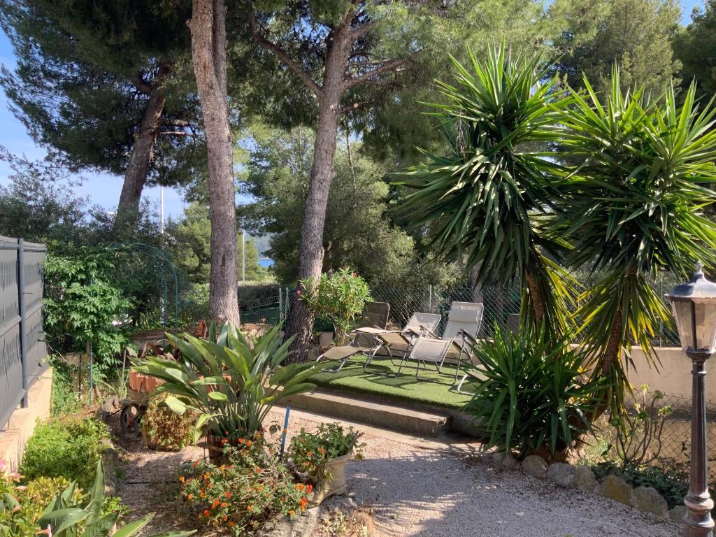 un jardin avec un banc et des palmiers dans l'établissement St Cyr sur mer appart 6pers avec jardin et parking A 30m de la plage, à Saint-Cyr-sur-Mer