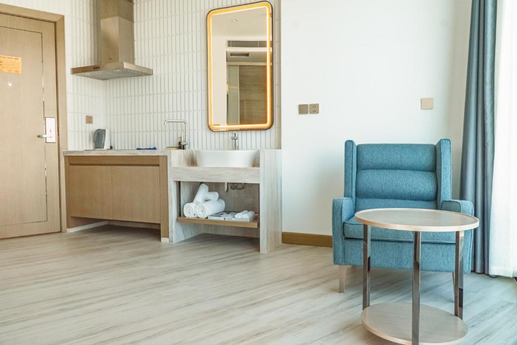 a bathroom with a sink and a blue chair and a table at Awaken Da Nang Hotel in Danang