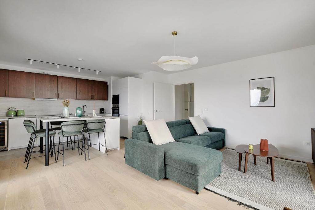 un salon avec un canapé bleu et une cuisine dans l'établissement Magnificent apartment- 3BR-8P-Proche de la Seine, à Clichy
