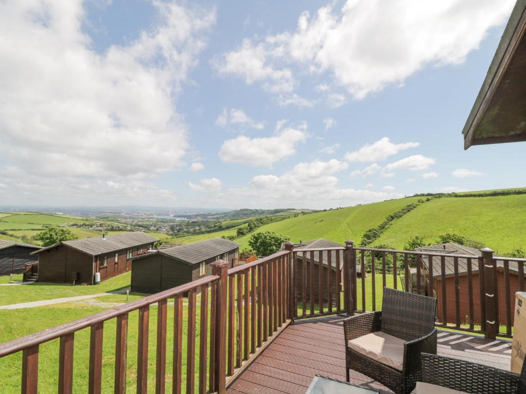 a deck with two chairs and a view of the countryside at Lodge 16 in Torpoint