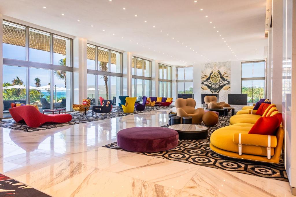 Un vestíbulo con sillas y mesas de colores y ventanas. en Hotel Mousai Cancun Ocean Front Adults Only - All Inclusive, en Cancún