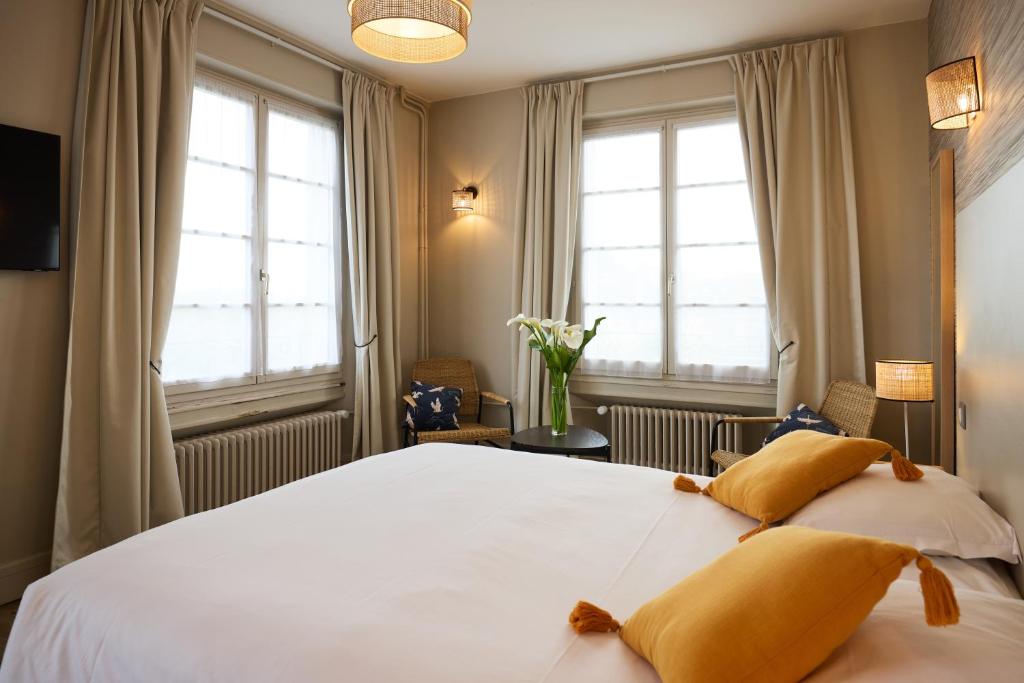 a bedroom with a large white bed with two pillows at Hôtel Marguerite in Orléans