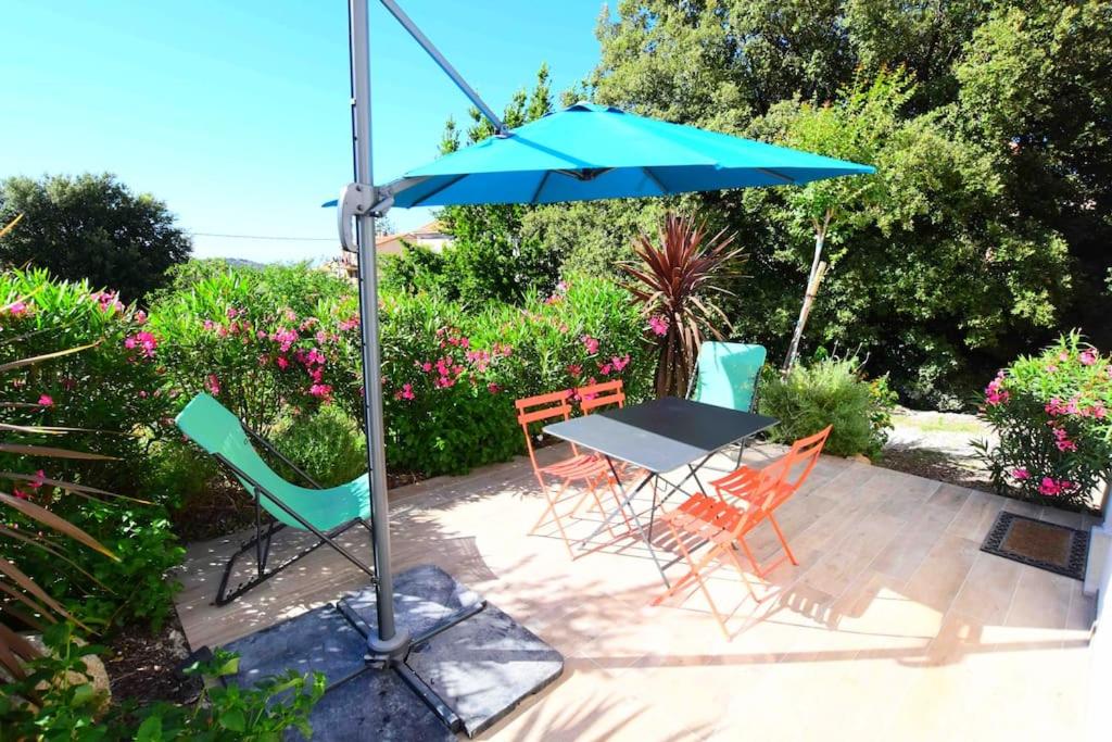 a table and chairs under an umbrella on a patio at Charmant appartement calme, avec terrasse fleurie in Calenzana