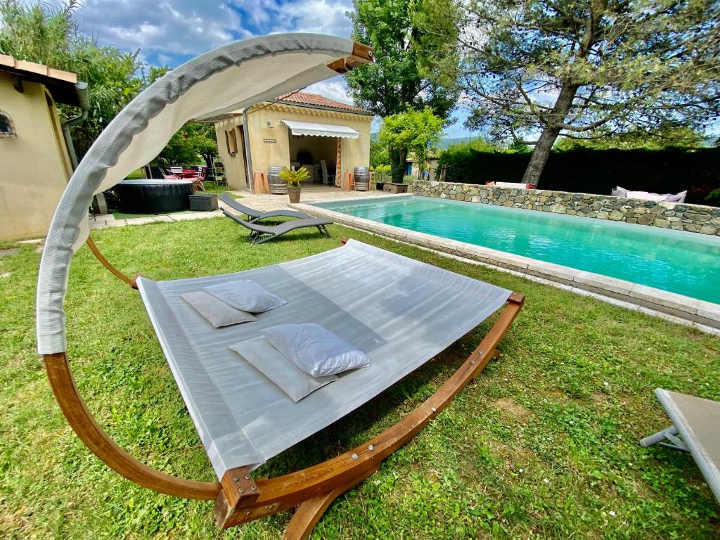 Una tumbona en el césped junto a una piscina. en Maison 6p, 3ch, piscine, jacuzzi, cuisine d'été, jardin clos, en Alba La Romaine
