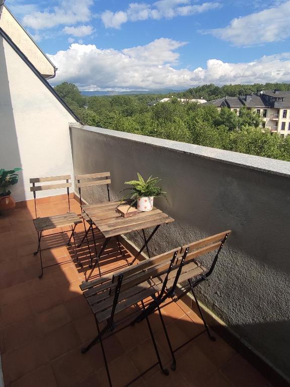 a balcony with two chairs and a wooden table with a plant at DÚPLEX SANABRIA in El Puente