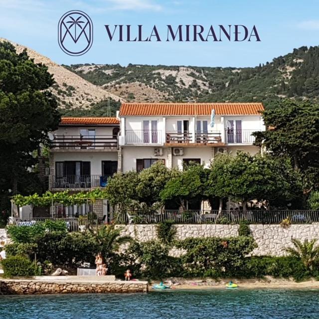 a building on the shore of a body of water at Apartments Vila Miranda on the beach in Barbat na Rabu