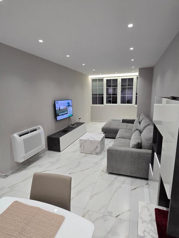 a living room with a couch and a tv at Prestige Beach Apartment in Durrës