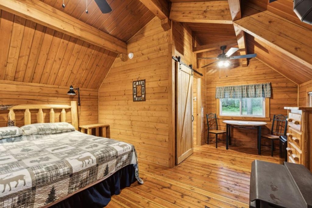 a bedroom in a log cabin with a bed and a table at Lost Horse Lodge King Cabin 12 in Darby
