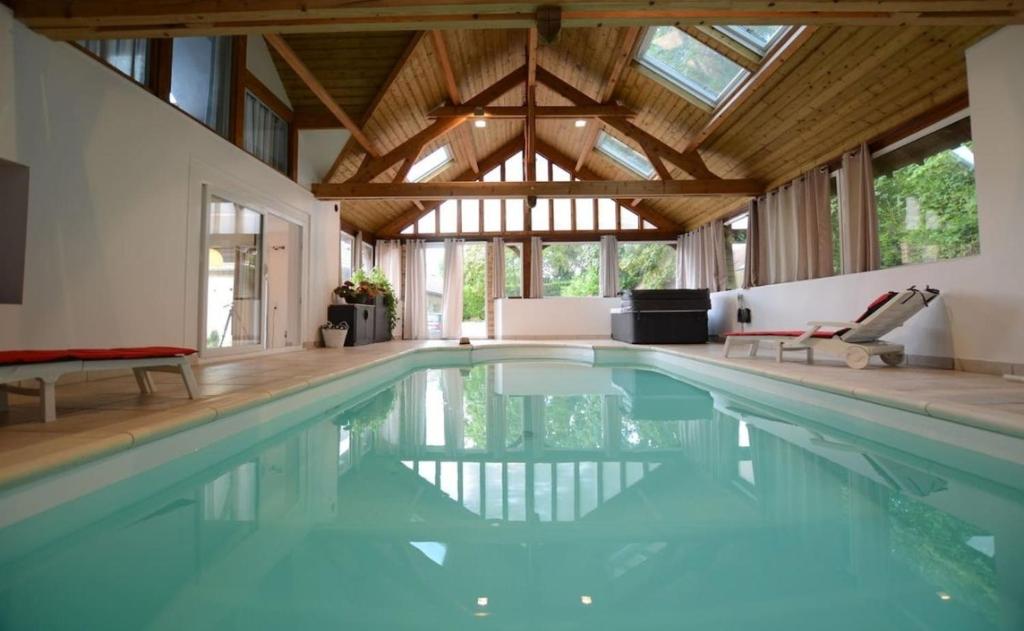 - une piscine dans une maison dotée d'un plafond en bois dans l'établissement Gite Des Ameraudes, à Macey