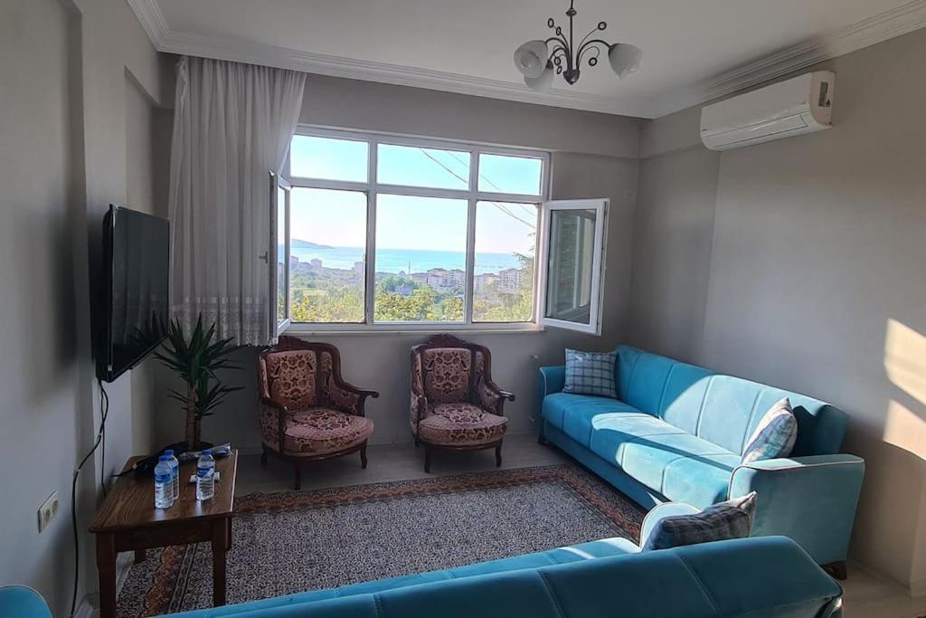 a living room with a blue couch and a window at Deniz ve Doğa Manzaralı Daire Arsin-Trabzon in Arsin