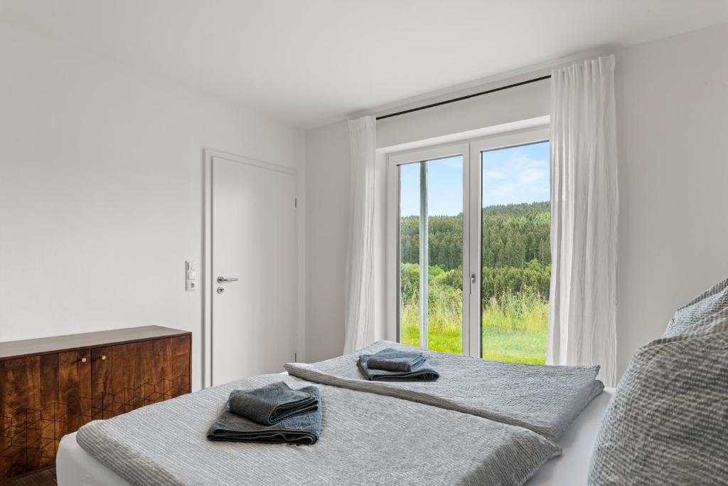ein weißes Schlafzimmer mit einem Bett mit Handtüchern darauf in der Unterkunft Neubau! Ökologischer Wellnessurlaub in der Eifel in Kopp