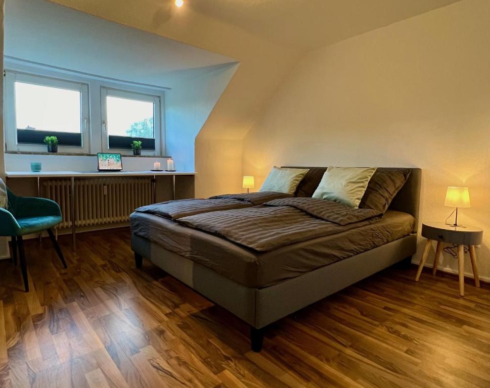 a bedroom with a large bed and two windows at Charmante Stadtwohnung mit Blick ins Grüne in Lübeck