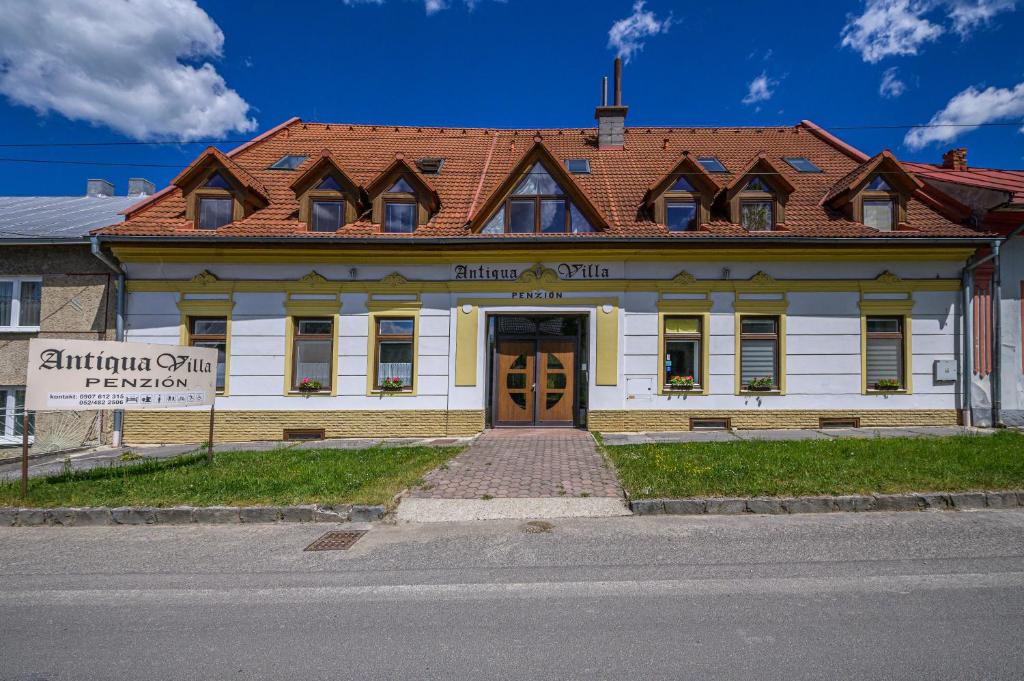 a white building with a brown door on a street at Penzión Antiqua Villa in Spišská Stará Ves