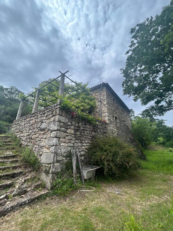 un ancien bâtiment en pierre avec une croix au-dessus dans l'établissement Le Mas du Savel, à Gagnières