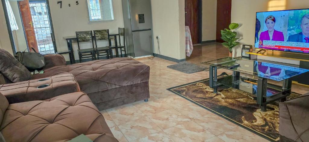a living room with couches and a flat screen tv at EAGLE WEAVERS NEST in Livingstone