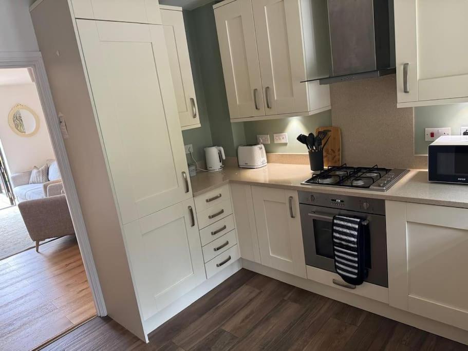 a kitchen with white cabinets and a stove top oven at Church Court 2 Bed 55 Inch SKY TV Northampton Parking Contractor Accommodation in Earls Barton