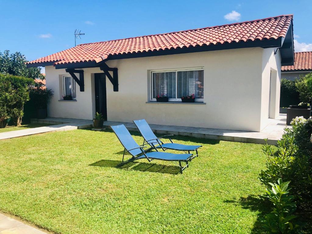 two blue chairs sitting on a lawn in front of a house at Détente et évasion entre Hossegor et Biarritz in Tarnos