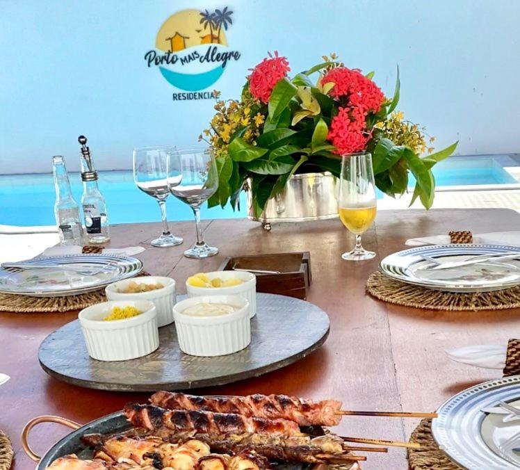 una tavola con piatti di cibo e bicchieri di vino di Apartamento Praia Porto mais Alegre a Porto Seguro