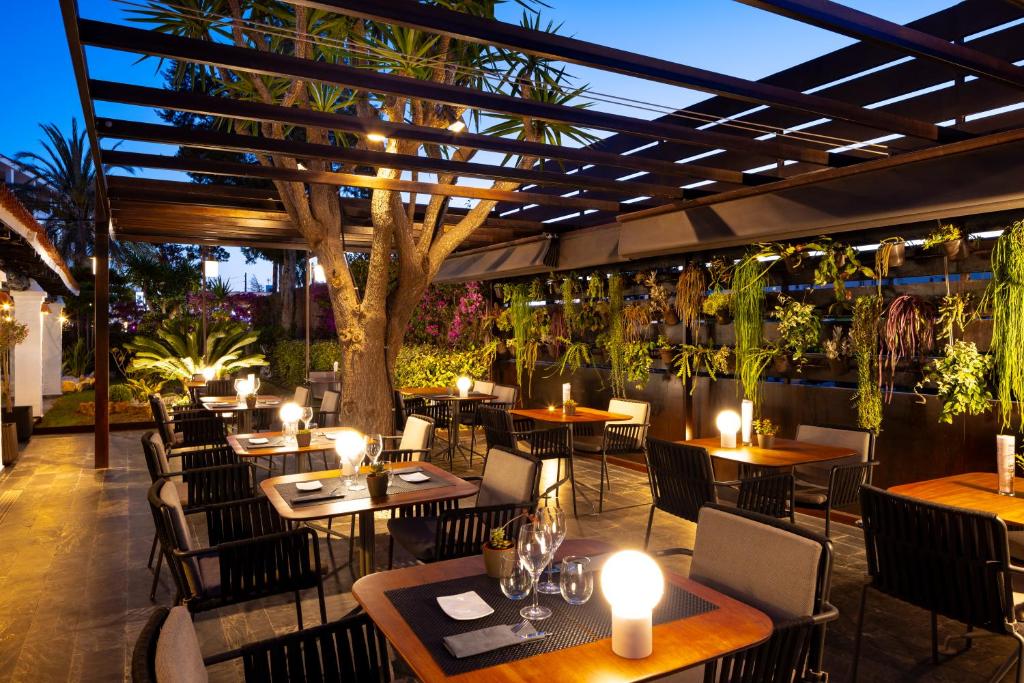 a restaurant with tables and chairs and a tree at Hotel Boutique Ses Pitreras in San Antonio Bay
