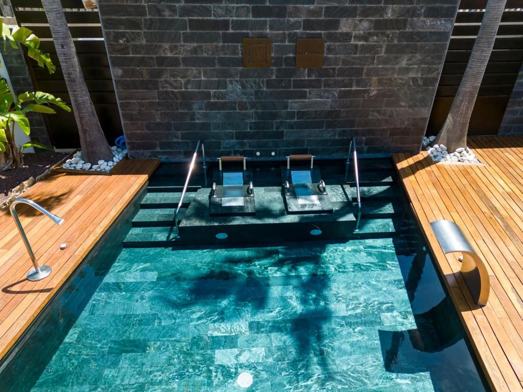 a swimming pool with two chairs in front of a brick wall at Hotel Boutique Ses Pitreras in San Antonio Bay