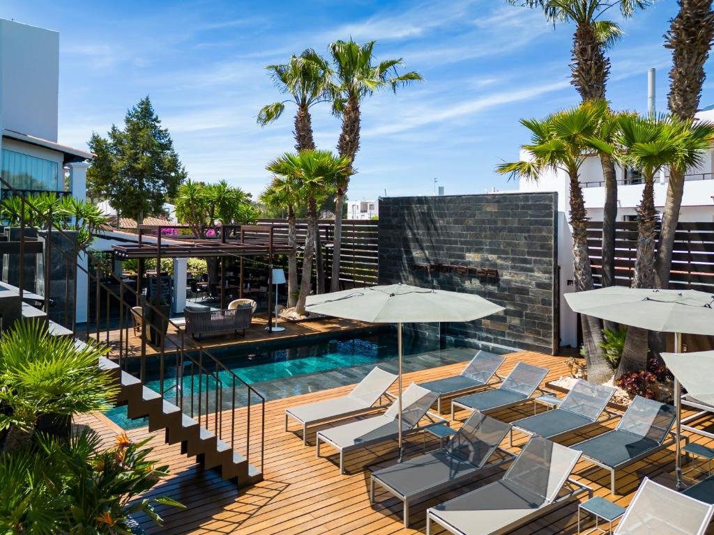 a swimming pool with lounge chairs and umbrellas at Hotel Boutique Ses Pitreras in San Antonio Bay