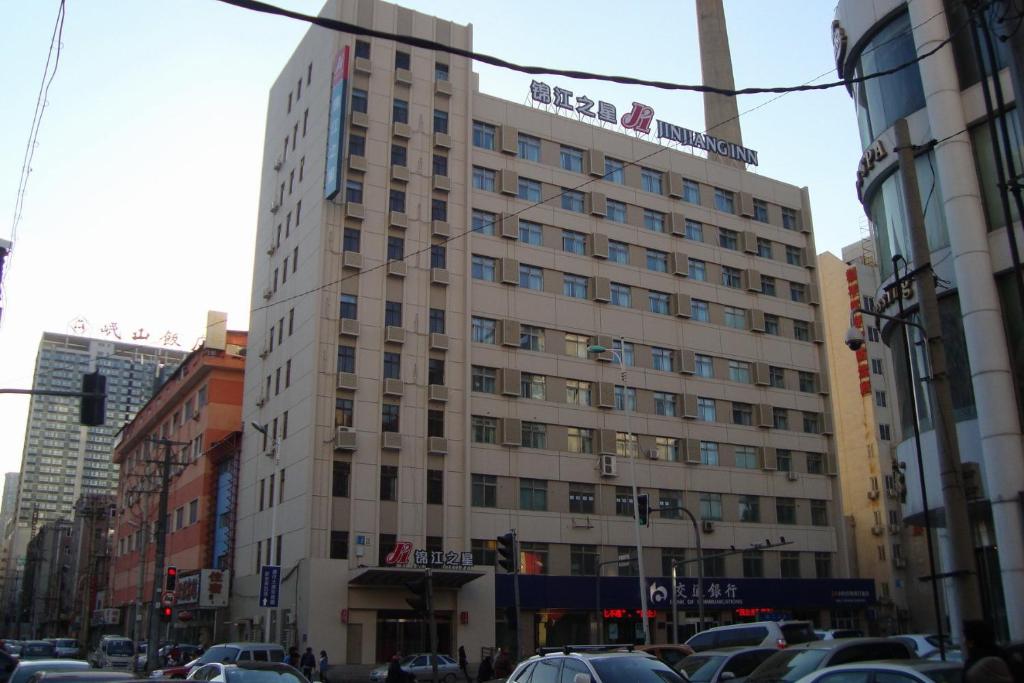 a tall white building on a city street with cars at Jinjiang Inn Wanda Plaza Hotel Taiyuan Street Shenyang in Shenyang