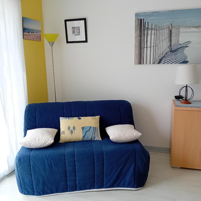- un canapé bleu avec des oreillers dans l'établissement Appartement 100m de la plage et des commerces, à LʼIsle-Saint-Cast