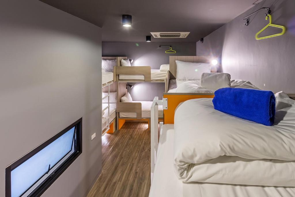 a room with two beds and a flat screen tv at iSanook Hostel in Bangkok