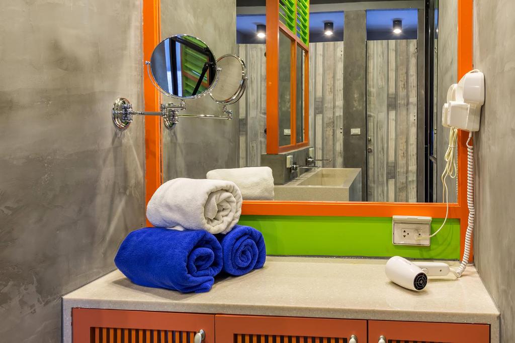 a bathroom with a sink and a mirror and towels at iSanook Hostel in Bangkok