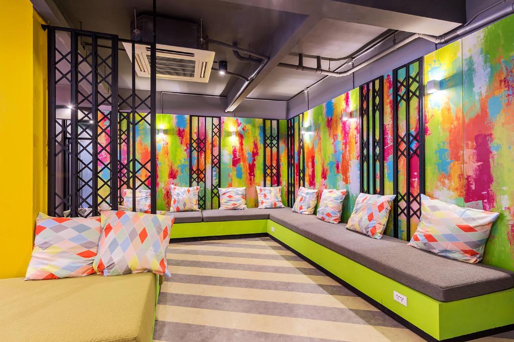 a room with colorful walls and a bench with pillows at iSanook Hostel in Bangkok