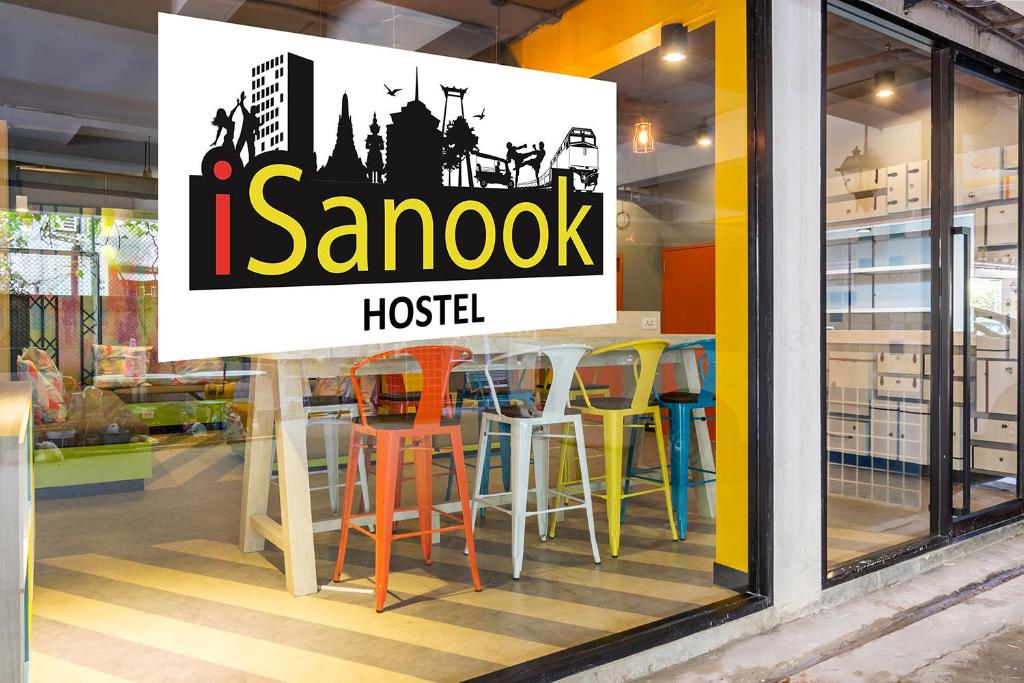 a sign in the window of a restaurant with colorful stools at iSanook Hostel in Bangkok