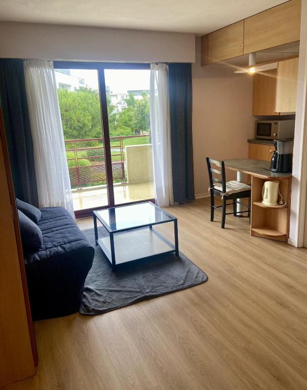 un salon avec un canapé et une table en verre dans l'établissement La Rochelle Minimes - Studio meublé avec piscine, à La Rochelle