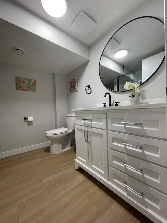 a bathroom with a sink and a toilet and a mirror at Flora's House in Calgary