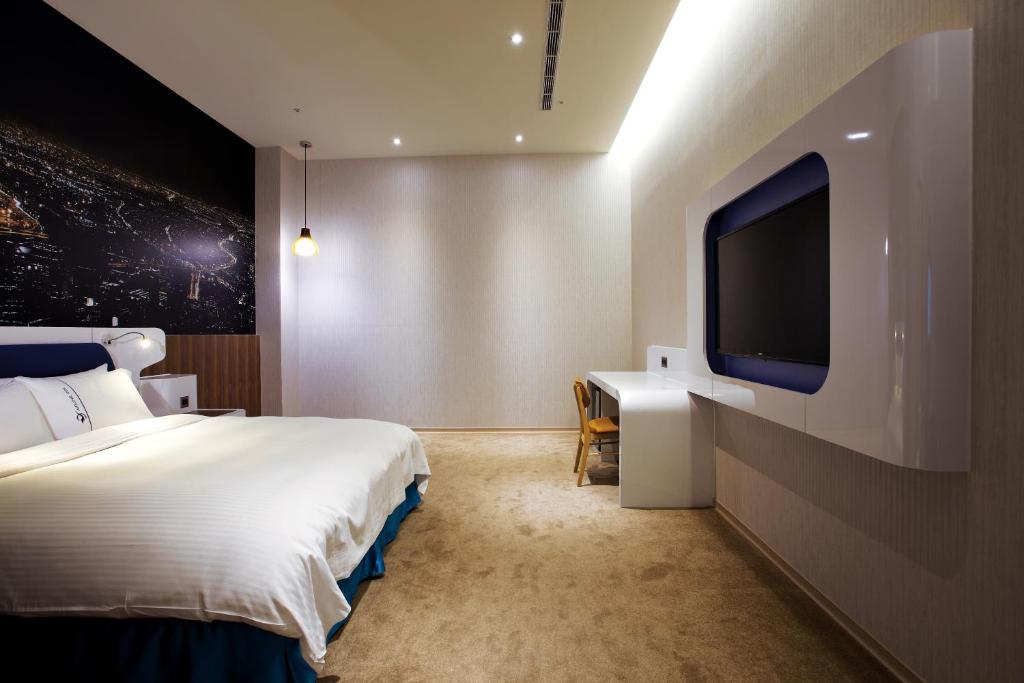 a hotel room with a bed and a flat screen tv at Airline Inn Green Park Way in Taichung