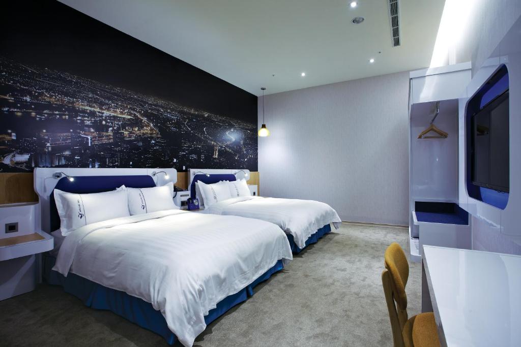 a hotel room with two beds and a flat screen tv at Airline Inn Green Park Way in Taichung