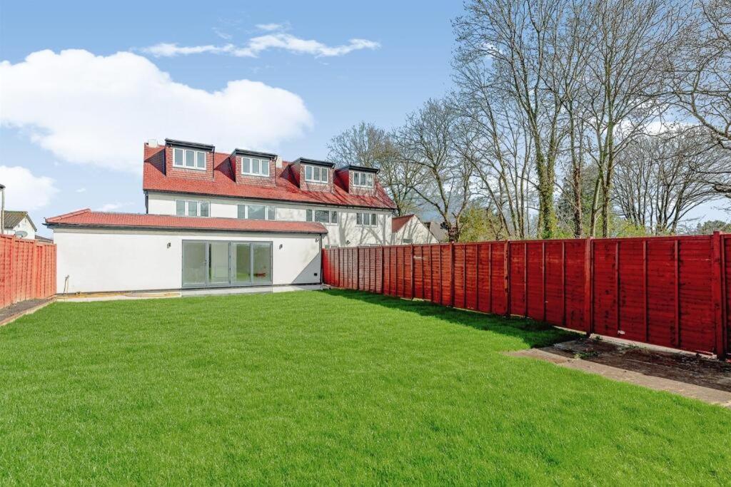 ein roter Zaun vor einem Haus in der Unterkunft 1 Orchard Farm Cottages Sleeps 10, Open plan Kitchen & Large Garden in East Grinstead