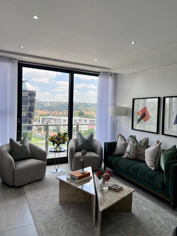 Una sala de estar con un sofá verde y una mesa. en Delight Luxurious Apartments, en Johannesburgo