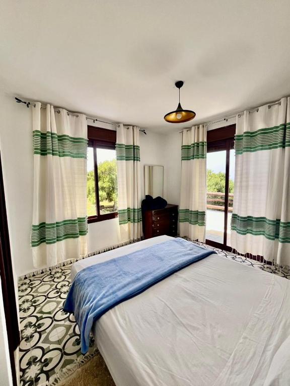 a bedroom with a large bed and windows at Dmina House in Asilah