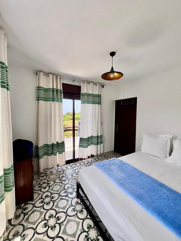 a bedroom with a large bed and a window at Dmina House in Asilah