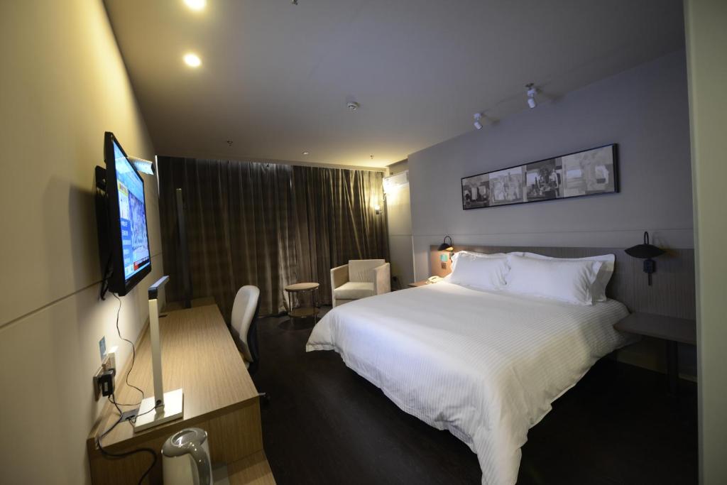 ein Hotelzimmer mit einem Bett und einem Flachbildfernseher in der Unterkunft Jinjiang Inn Yancheng Dongtai Municipal Government in Dongtai