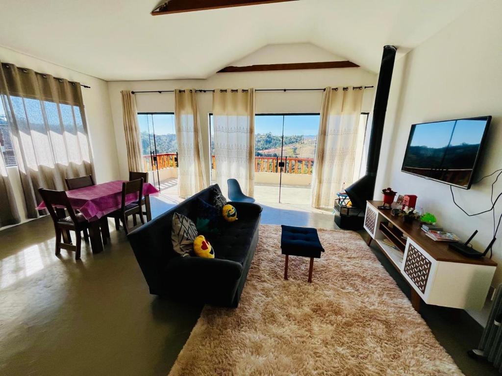 un salon avec un canapé, une télévision et une table dans l'établissement Chalé Vista Linda, à Campos do Jordão