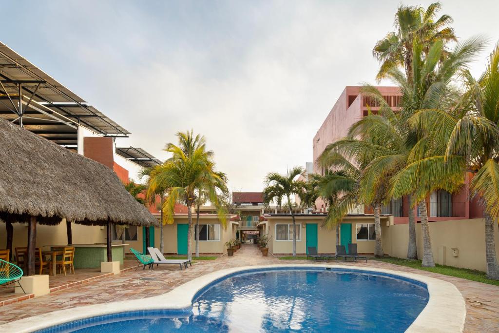 a resort with a swimming pool and palm trees at Bungalows Las Arenas in San Patricio Melaque