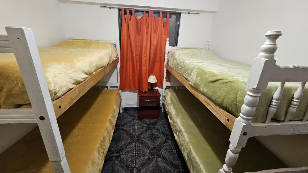 a bedroom with two bunk beds and an orange curtain at Hospedaje Familiar Janaq Pacha in San Salvador de Jujuy