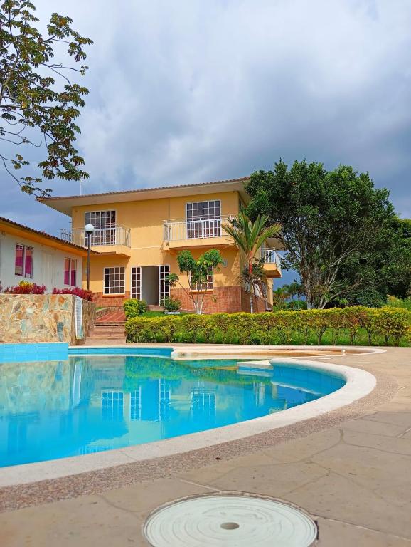 a swimming pool in front of a house at Finca Hotel el Amanecer in Quimbaya