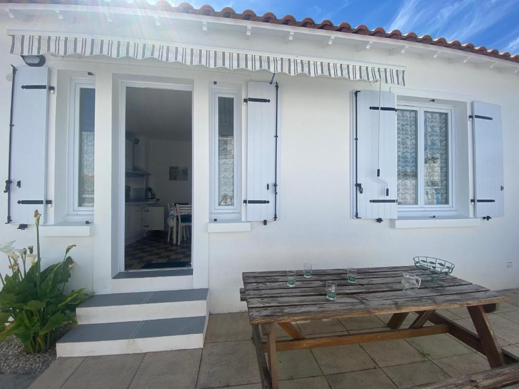 une maison blanche avec une table en bois devant elle dans l'établissement Charmant T2 avec Terrasse Privée, à 600m Plage et Commerces, La Tranche-sur-Mer - FR-1-22-278, à La Tranche-sur-Mer