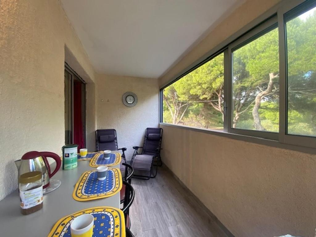 - deux tables et des chaises dans une chambre avec fenêtres dans l'établissement T2 à Narbonne-Plage - Parking & Proche Plage - 5 Pers - FR-1-795-5, à Vert-le-Grand