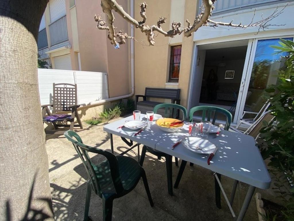 une table bleue avec des chaises sur la terrasse dans l'établissement Coquet T2 à Narbonne Plage - Cour arborée, Parking, Proche plage et commerces, 4 pers. - FR-1-795-14, à Narbonne